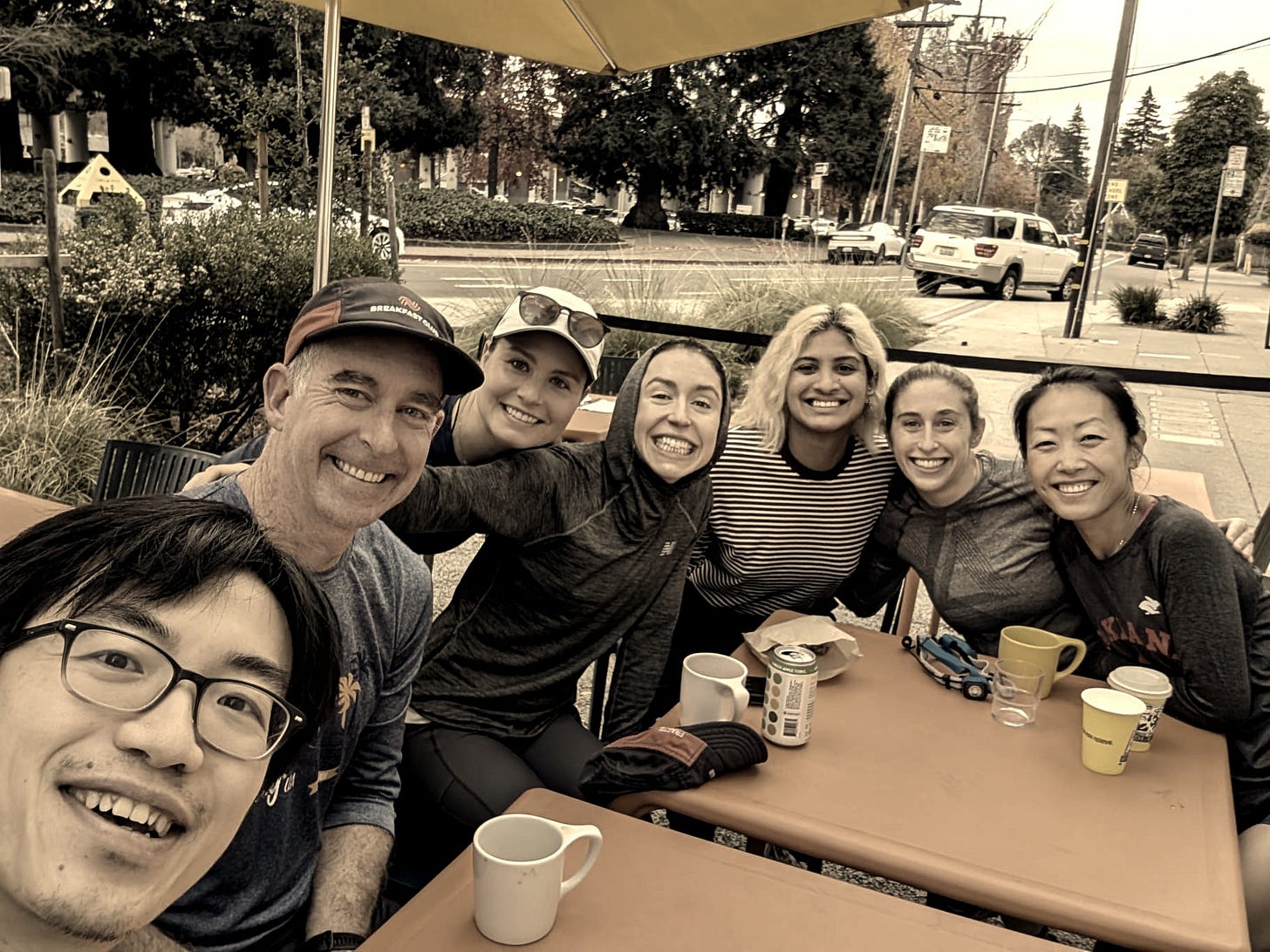 Image of small group of people posing for photo while drinking coffee.