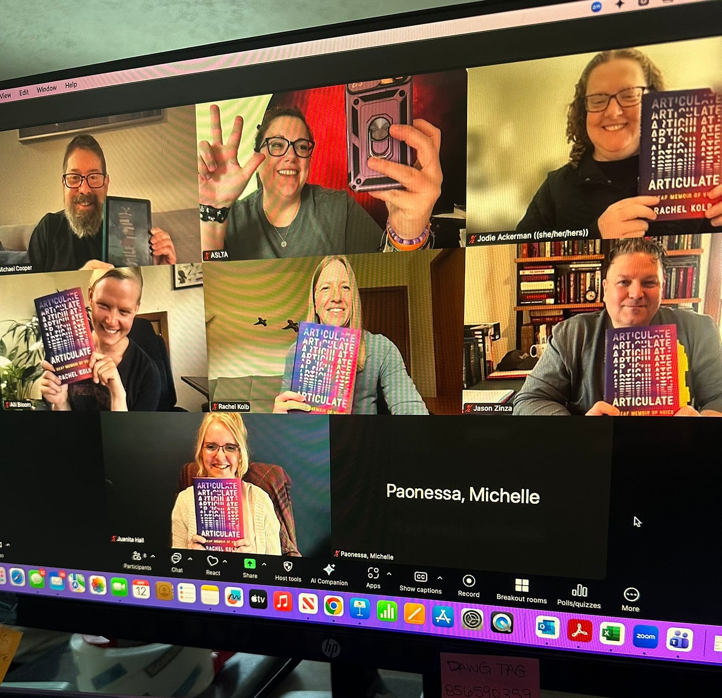 A photo of a computer screen, featuring a Zoom window open in gallery view with seven people visible onscreen. All of us, including me, are holding up copies of my book ARTICULATE and smiling at the camera.
