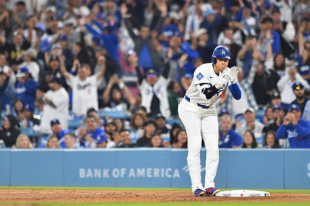 Los Angeles Dodgers designated hitter Shohei Ohtani celebrates after his base hit drives in a run during the MLB game between the Atlanta Braves and...