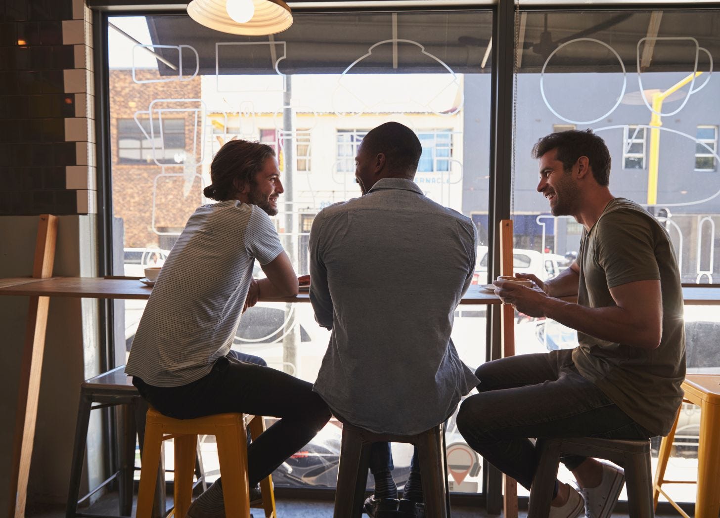 Three people talking at a café window, symbolizing local partnerships and community collaboration. Three people talking at a café window, symbolizing local partnerships and community collaboration.