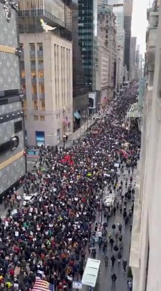 High-angle view of a massive crowd marching down a New York City street during a protest.