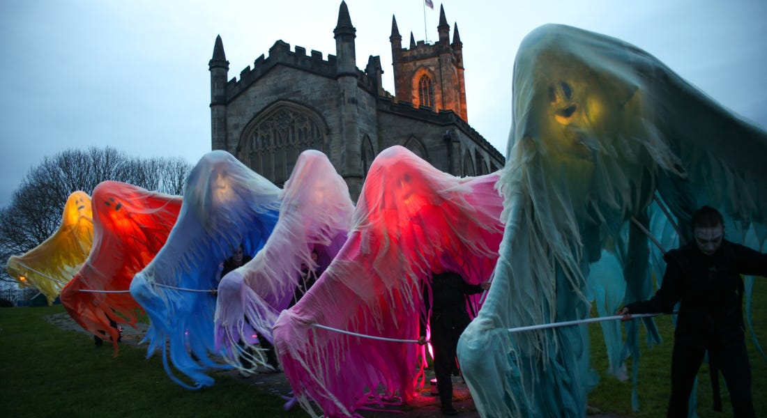 A collection of colourful ghosts standing outside a church