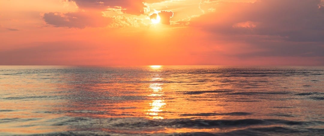 sea under white clouds at golden hour