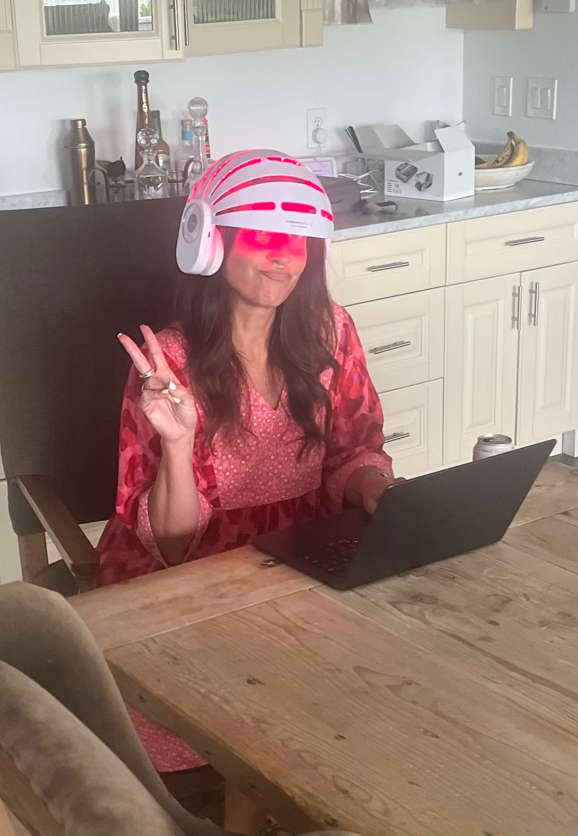 Woman wearing a red light hair growth helmet and an LED face mask at her desk, looking like a high-tech sci-fi character. Woman wearing a red light hair growth helmet and an LED face mask at her desk, looking like a high-tech sci-fi character.