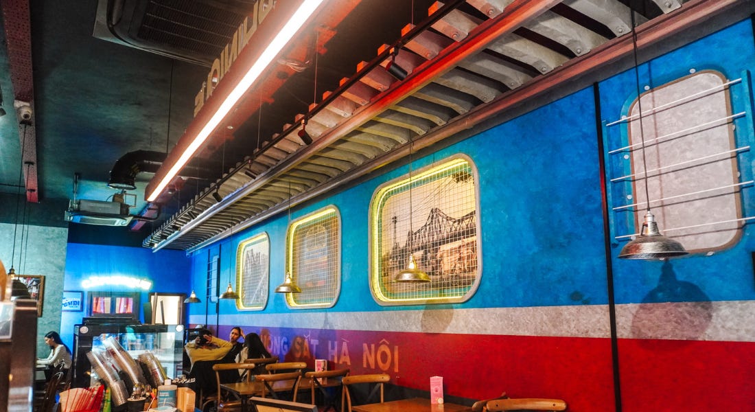 A restaurant with a subway-style wall, wooden tables, and neon lights