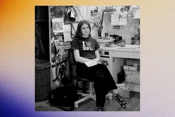 A black-and-white photo of a teenage girl sitting at a desk with a book in her lap.
