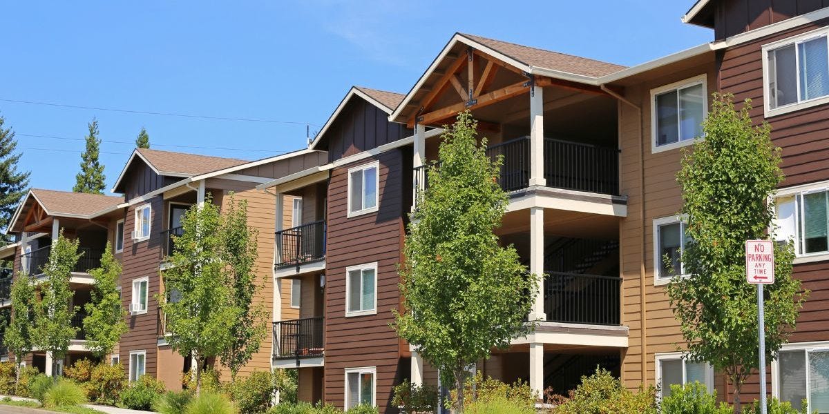 apartment complex with trees in front on a sunny day