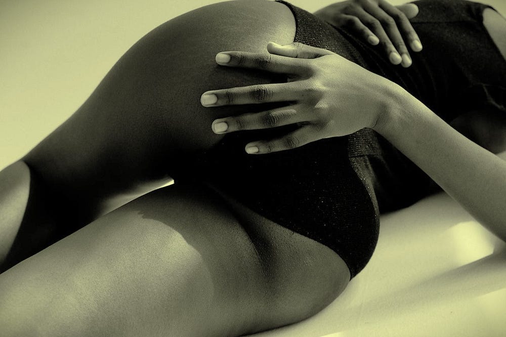 A woman's torso with a hand on her bottom A woman's torso with a hand on her bottom