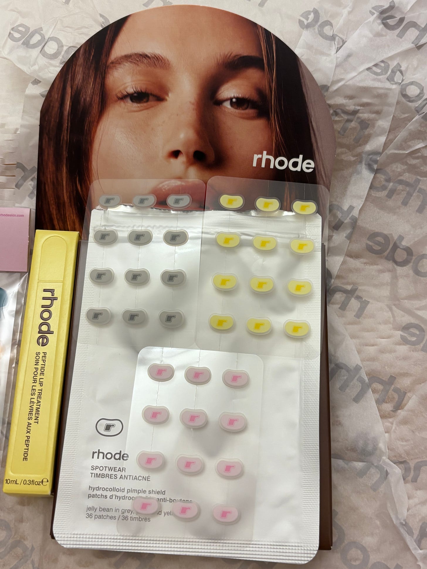 Rhode Spotwear Jelly Bean pimple patches alongside the Peptide Lip Treatment in Caramelised Banana yellow packaging.