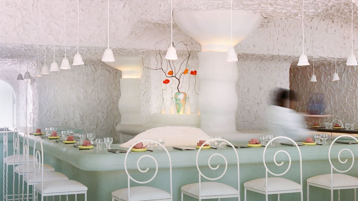 Interior of Cento Raw Bar with a seafoam green bar, ice pile, and metal chairs.