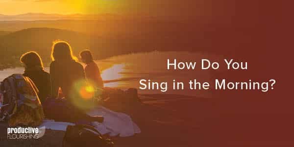 Frieds sit on a rocky ledge watching a sunrise over the water. Text Overlay: How Do You Sing In the Morning? Frieds sit on a rocky ledge watching a sunrise over the water. Text Overlay: How Do You Sing In the Morning?