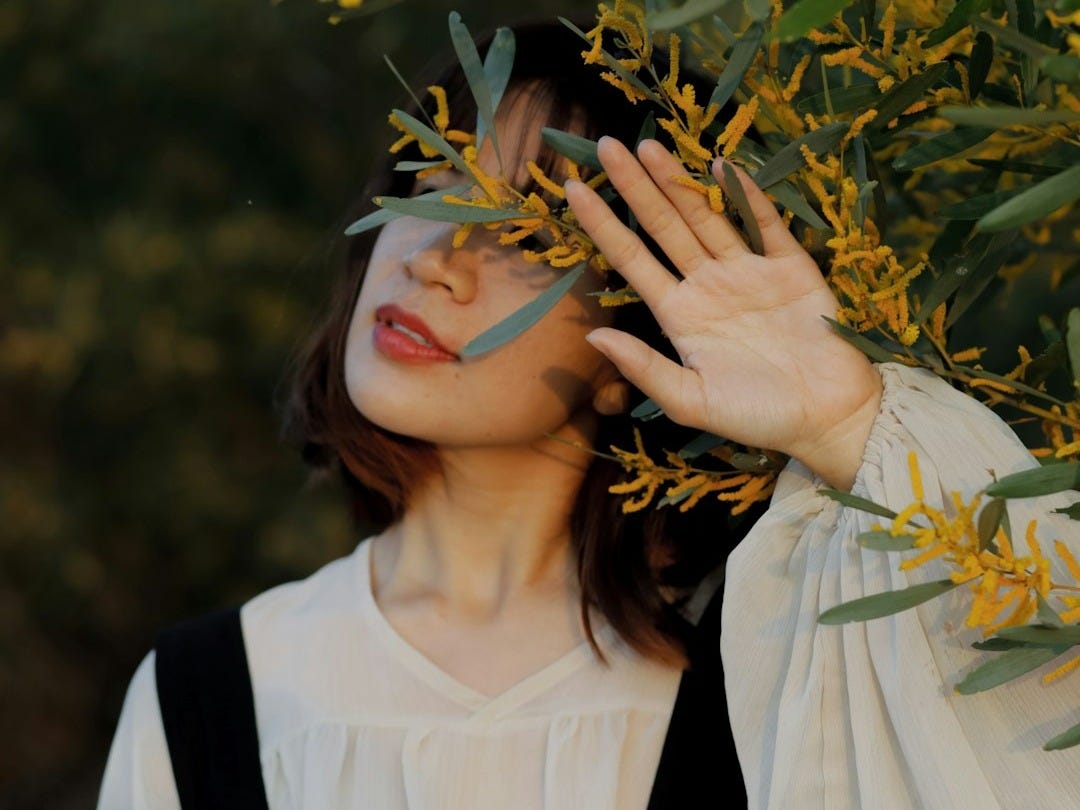 woman in white and black school uniform holding yellow leaves
