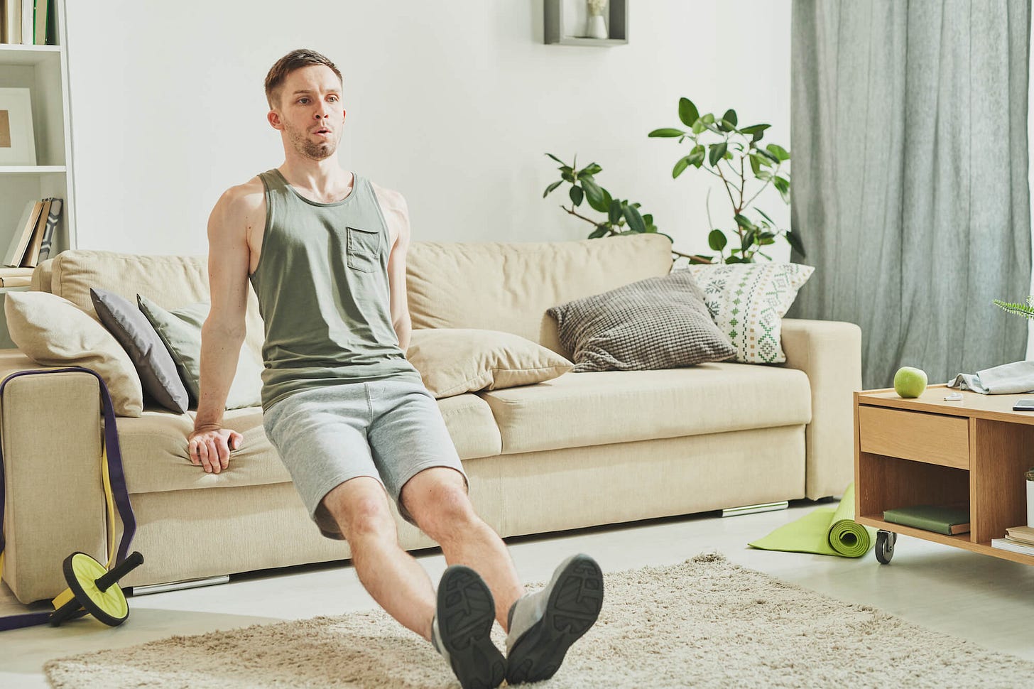 A young, muscular man doing light exercise at home