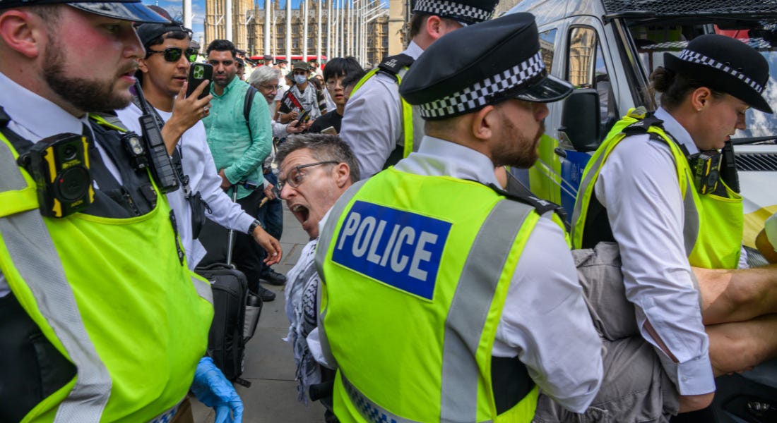 A group of police officers carrying a man who is shouting