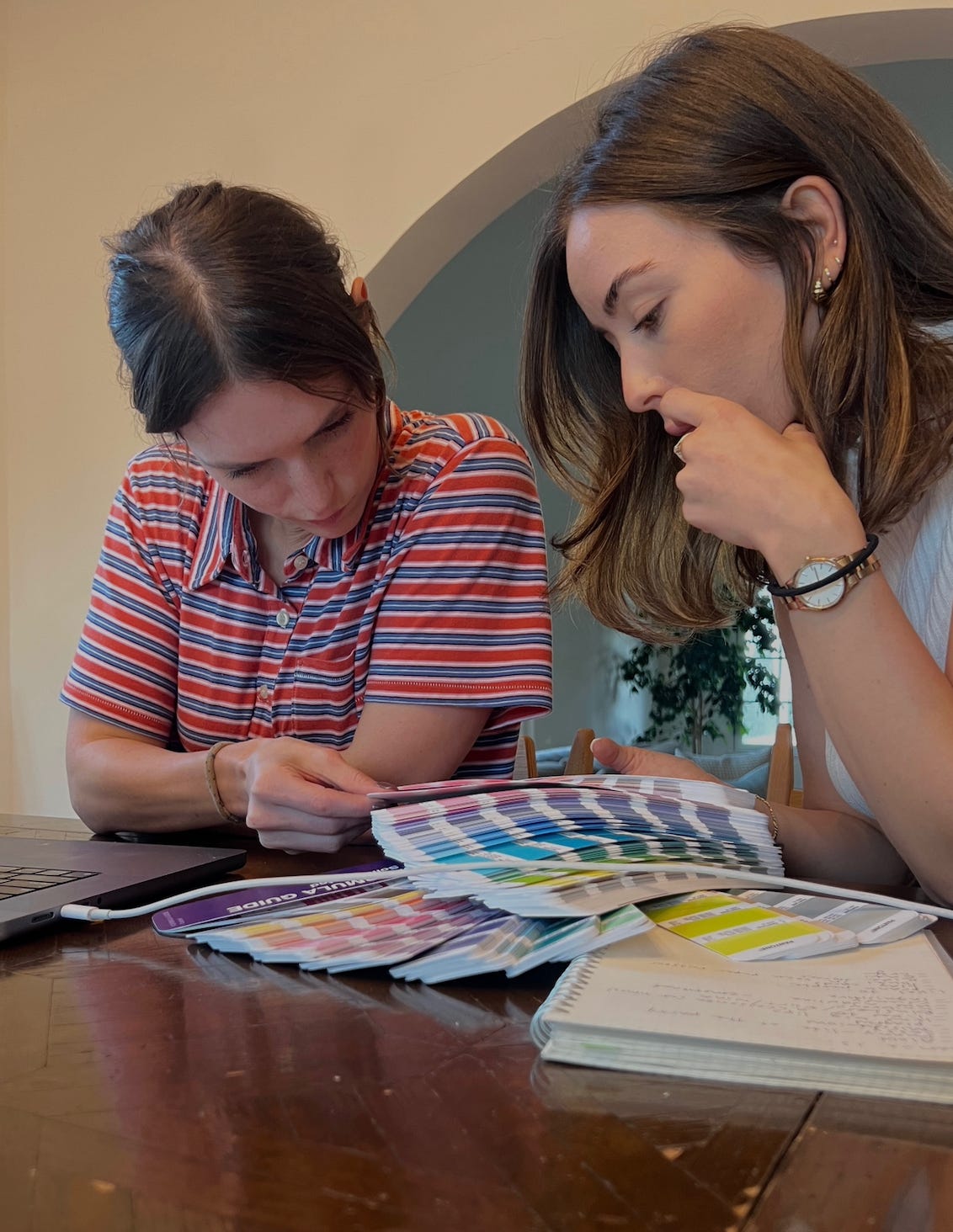 Benjie co-founders Tessa Cohen and Sara Sebastjanska reviewing colorful bandage design samples at a table with a laptop and notebook.
