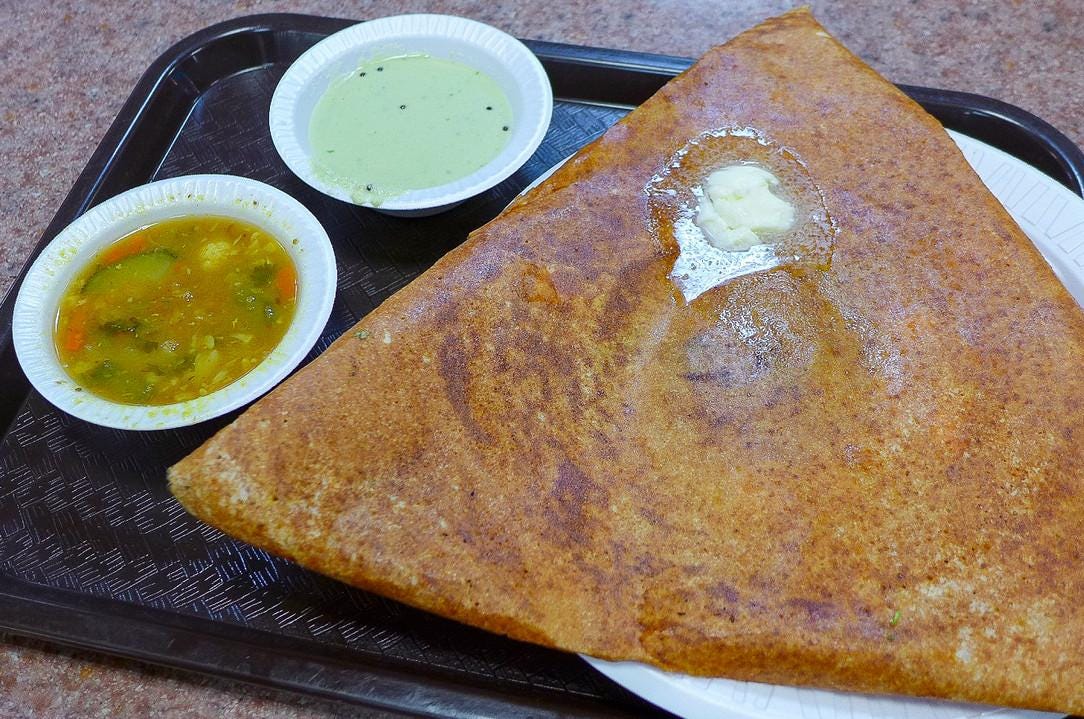 A triangular dosa with coconut chutney and sambar.