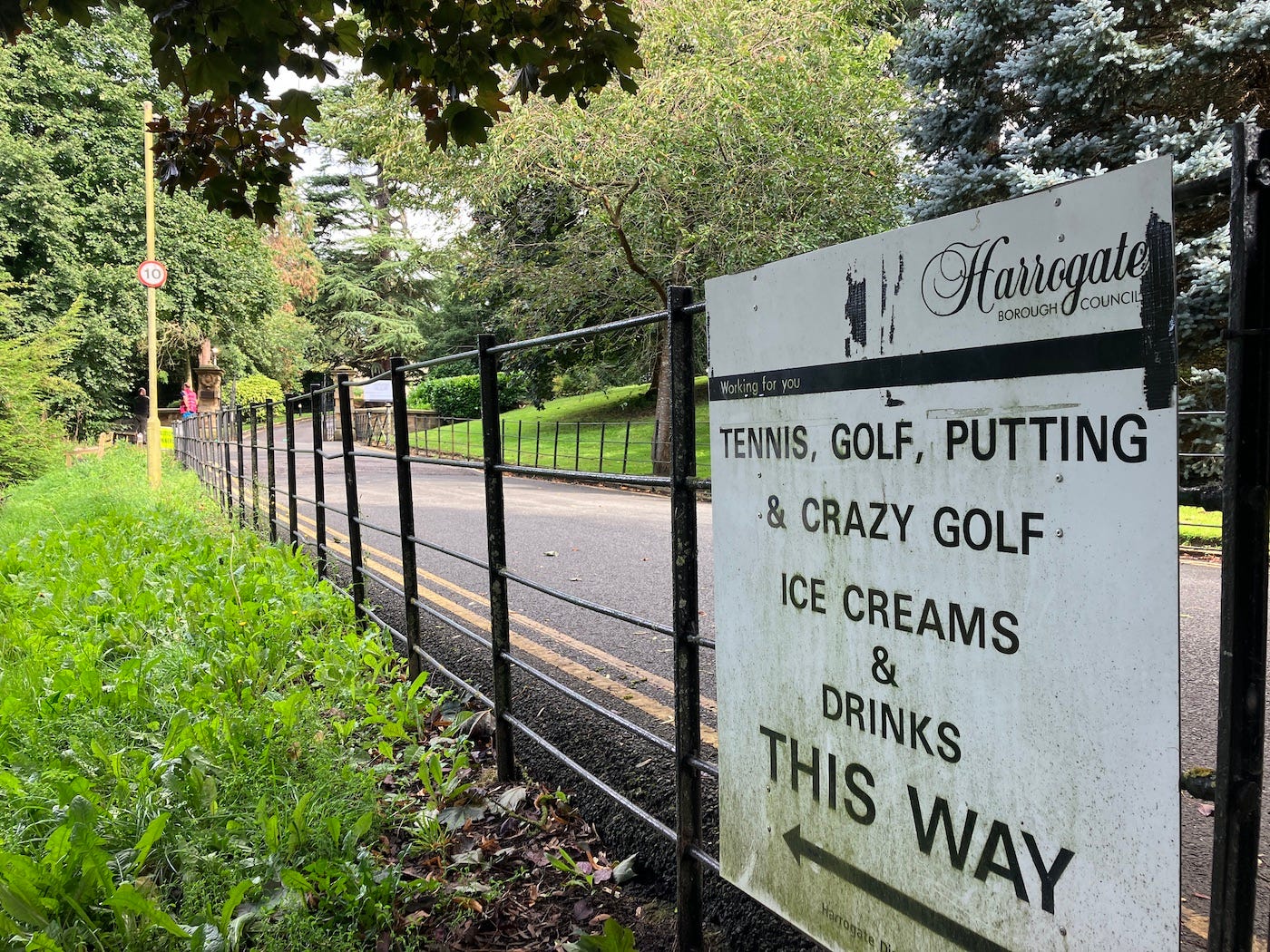 Sign on railings offers 'tennis, golf, putting & crazy golf, ice creams & drinks