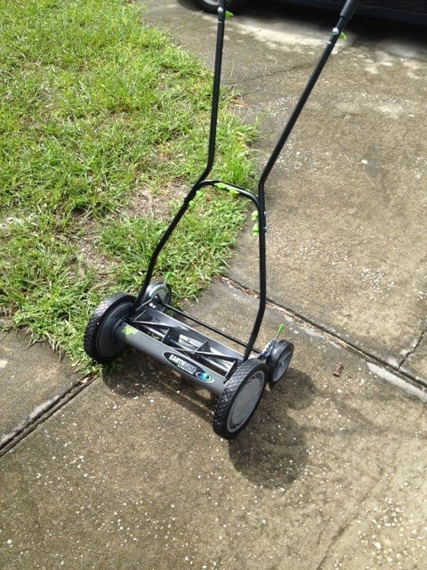 Photo of a rotary self powered lawn mower sitting on a driveway.