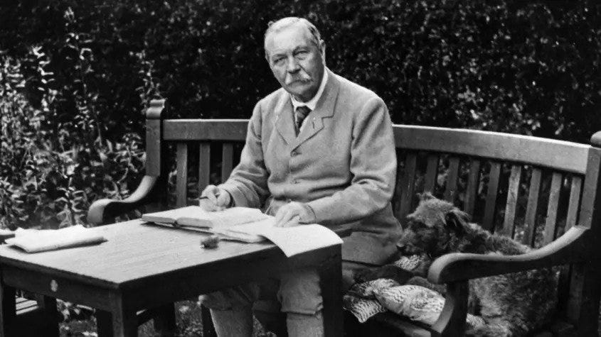 Picture of Arthur Conan Doyle sitting outside, writing at a table.