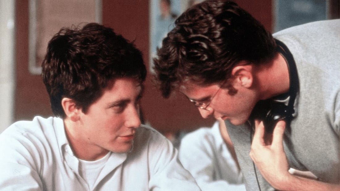 Двама млади мъже разговарят оживено, единият седнал, а другият наведен напред. И двамата са облечени в ежедневни дрехи на закрито с размазан фон на фигури. Двама млади мъже разговарят оживено, единият седнал, а другият наведен напред. И двамата са облечени в ежедневни дрехи на закрито с размазан фон на фигури.