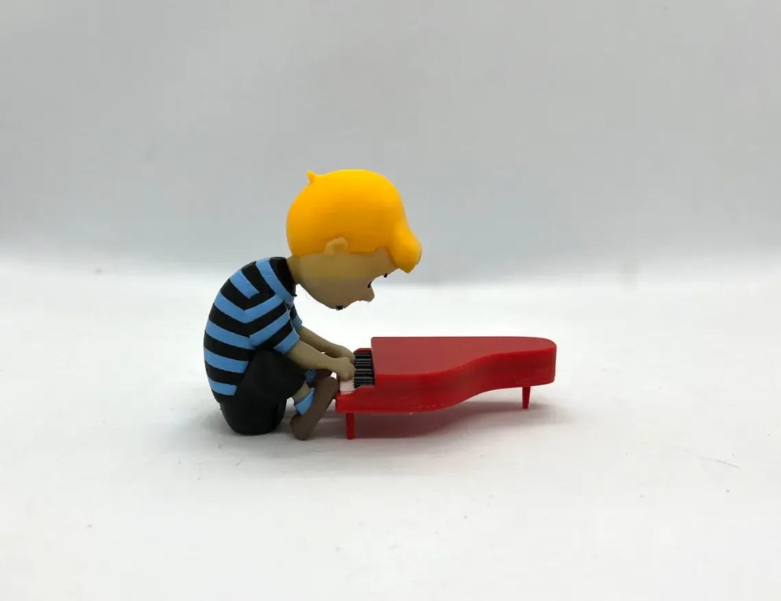 A small 3D printed Schroeder playing the piano against a stark white background, his face in shadow