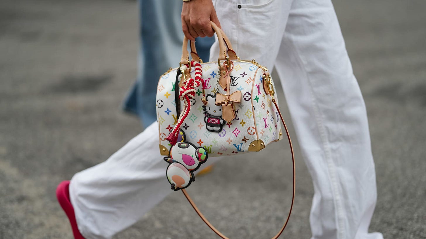 COPENHAGEN, DENMARK - AUGUST 04: Emili Sindlev wears white pants with a loose fit. In hand, a white Louis Vuitton leather handbag features a multicolored Louis Vuitton monogram pattern with gold hardware and tan leather handles. A red and white braided accessory with a Hello Kitty Charms and a Panda Superflat Louis Vuitton X 
Murakami keychain is attached to the bag, outside OperaSport, during Copenhagen Fashion Week, on August 04, 2025 in Copenhagen, Denmark (Photo by Edward Berthelot/Getty Images)