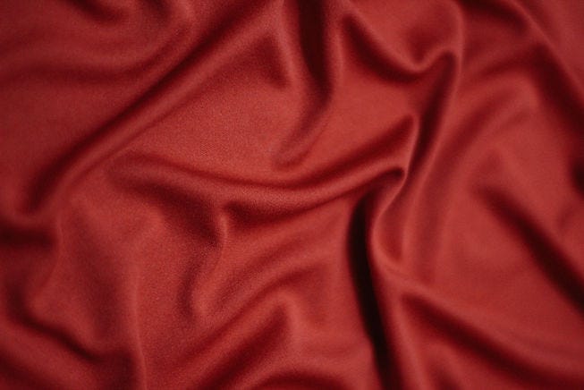Image is of crumpled red sheets.