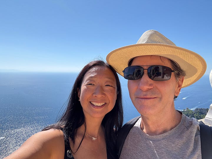 Collage of four images from Italy: Larry hiking the misty Path of the Gods, glowing blue water in Capri's Blue Grotto, me and Larry smiling in front of the ocean in the gardens of Ravello, and a table filled with seafood, vegetables, and wine.
