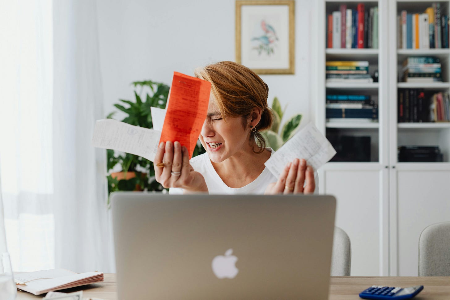 Woman struggling with receipts, at her desk with a laptop. Woman struggling with receipts, at her desk with a laptop.