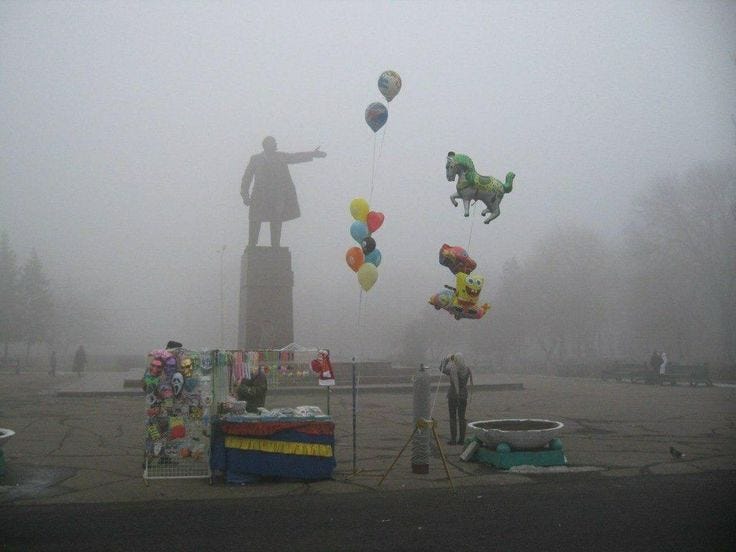 This may contain: several balloons are being flown in front of a statue on a foggy day with people looking at them This may contain: several balloons are being flown in front of a statue on a foggy day with people looking at them