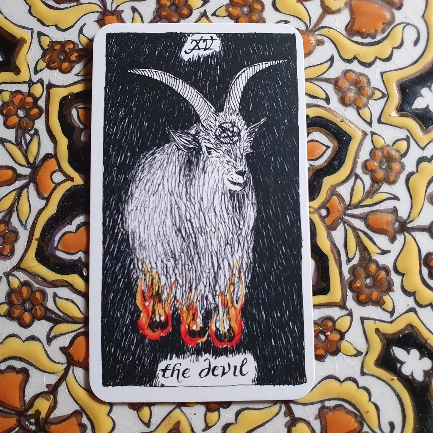 The Devil card in The Wild Unknown Tarot. Shown as a rather sweet goat with flaming hooves