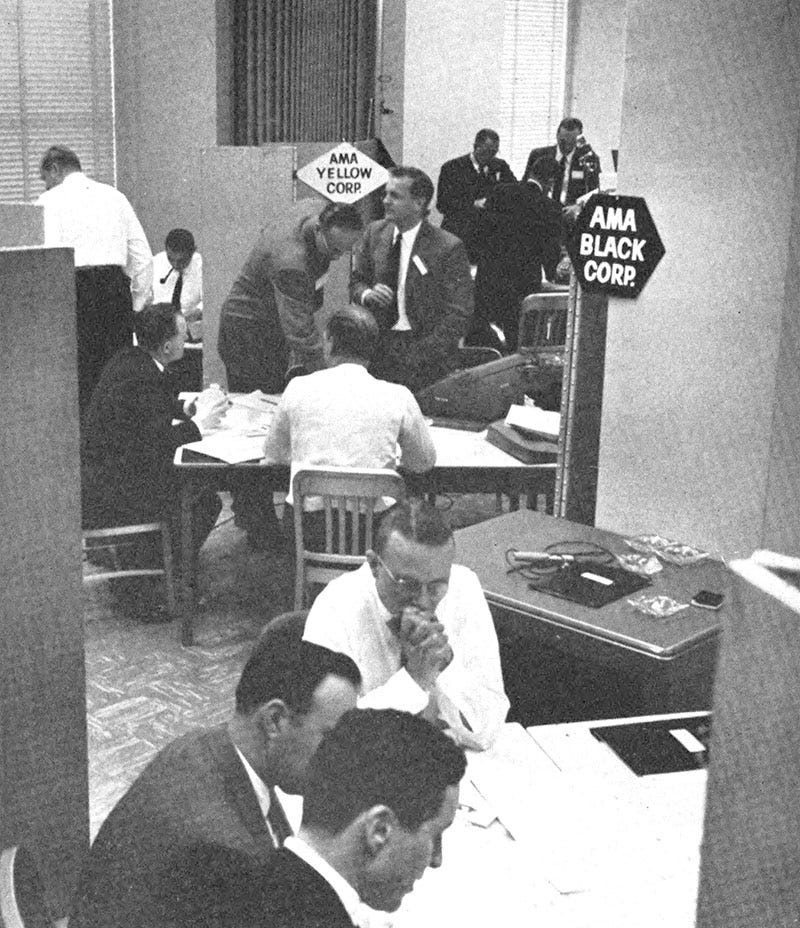 Groups of middle-aged executives gather at tables with signs reading "AMA Yellow Corp" and "AMA Black Corp"