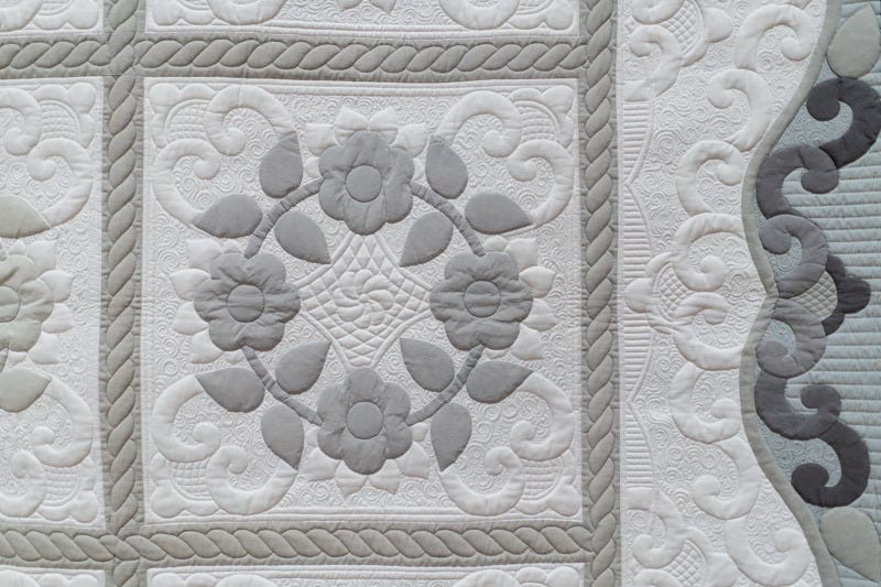 A close-up view of the gray and white quilt showcasing the intricate machine stitching by artist Karen McTavish A close-up view of the gray and white quilt showcasing the intricate machine stitching by artist Karen McTavish