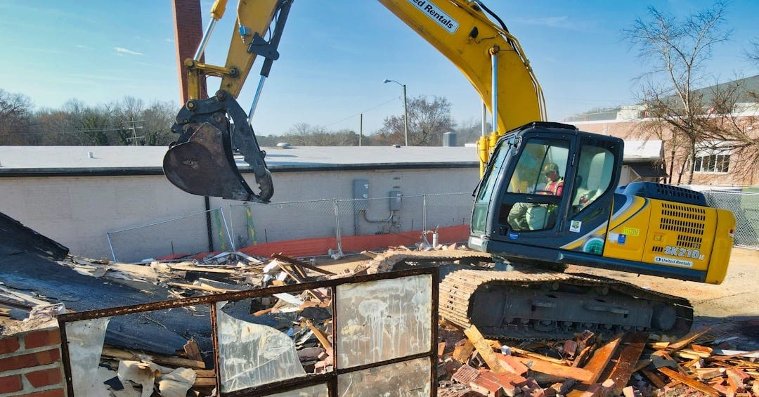 yellow and black excavator on brown brick wall during daytime