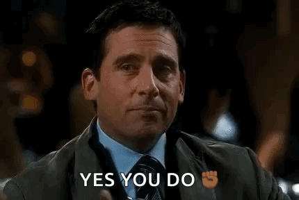 a man in a suit and tie is holding a drink in his hand and pointing at it . a man in a suit and tie is holding a drink in his hand and pointing at it .