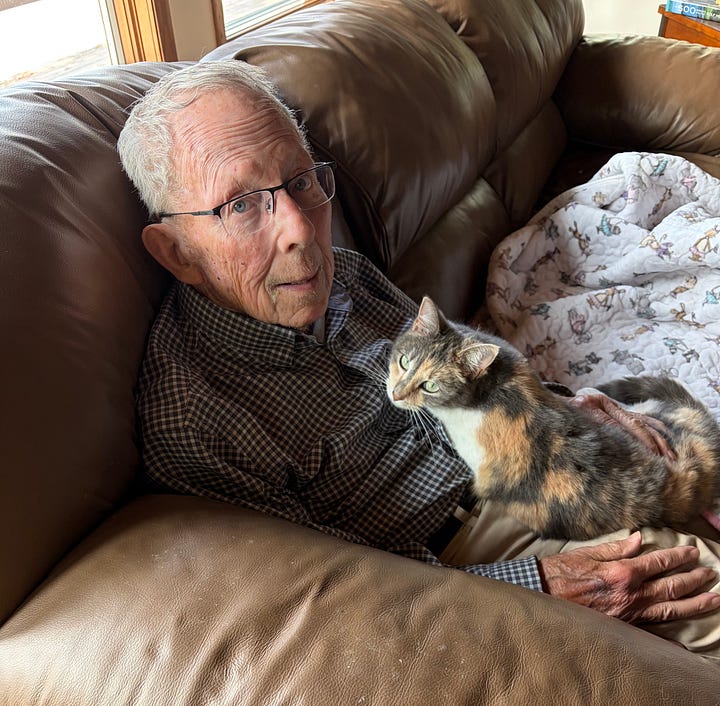 Man holding a white calico cat, baby bottle, and baby; Elderly man holding a cat