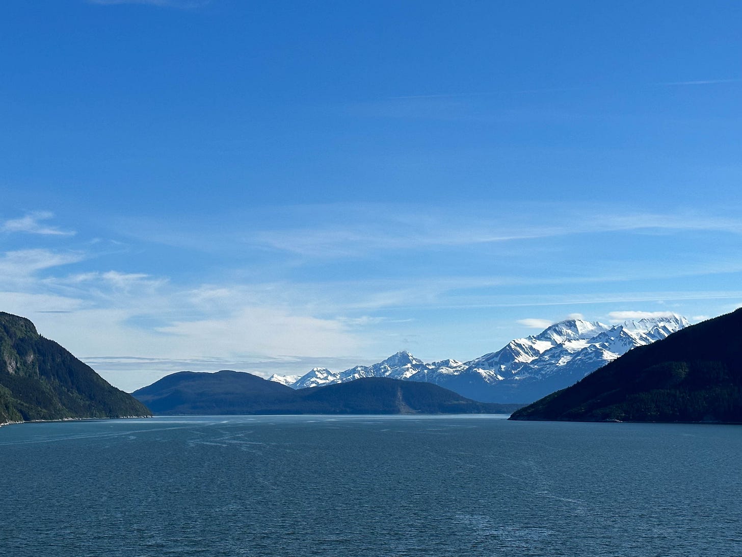 Blue sky, blue water, surrounded by snow-capped mountains.