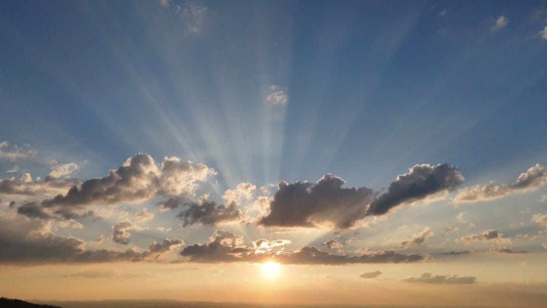 Sun rays bursting through clouds at sunset