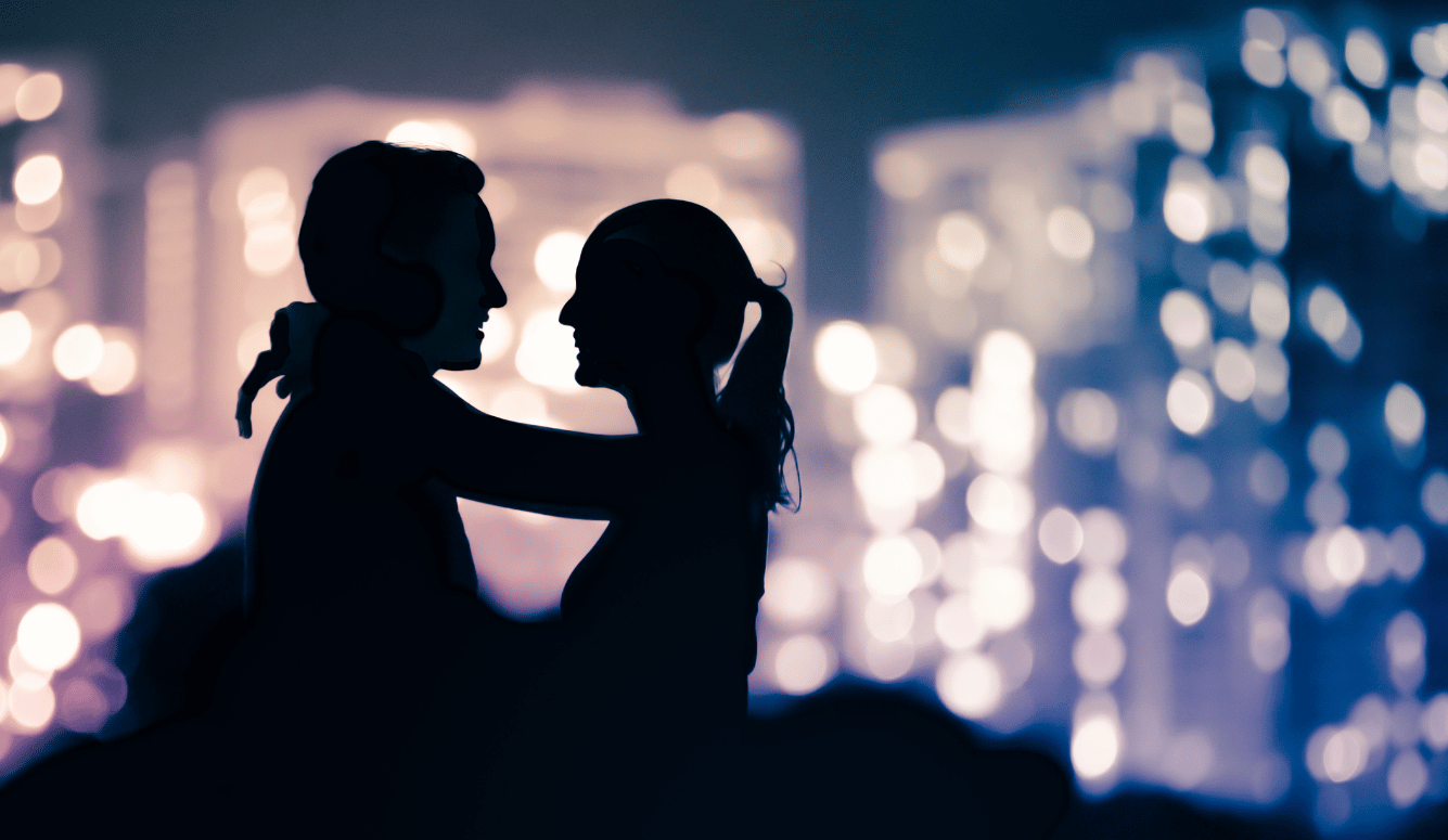 A silhouette of a heterosexual couple with arms around each other. A silhouette of a heterosexual couple with arms around each other.