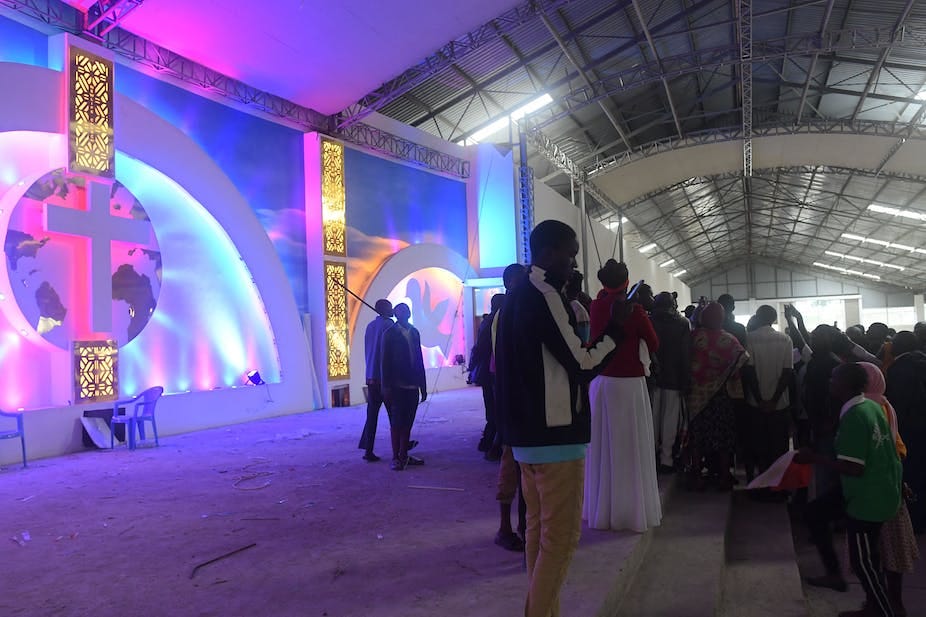 People gather in front of a stage with a cross People gather in front of a stage with a cross