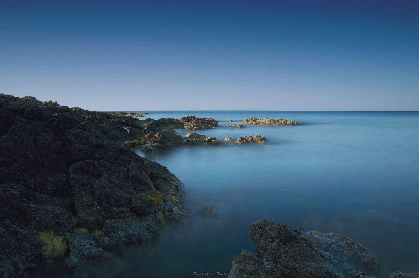 Mer laiteuse en pose longue qui vient ramper sur des rochers