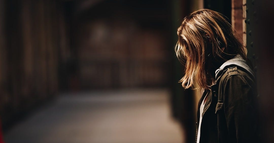 woman leaning against a wall in dim hallway