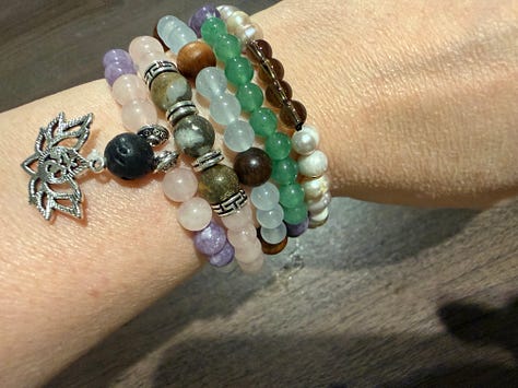 A variety of bead bracelets in various colors and pink mala beads and tiger's eye mala beads