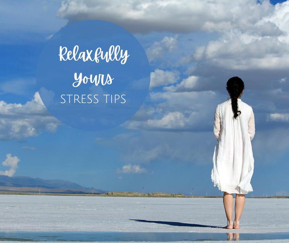 Back view of a woman in a white dress standing on the shore gazing at the sky and sea.