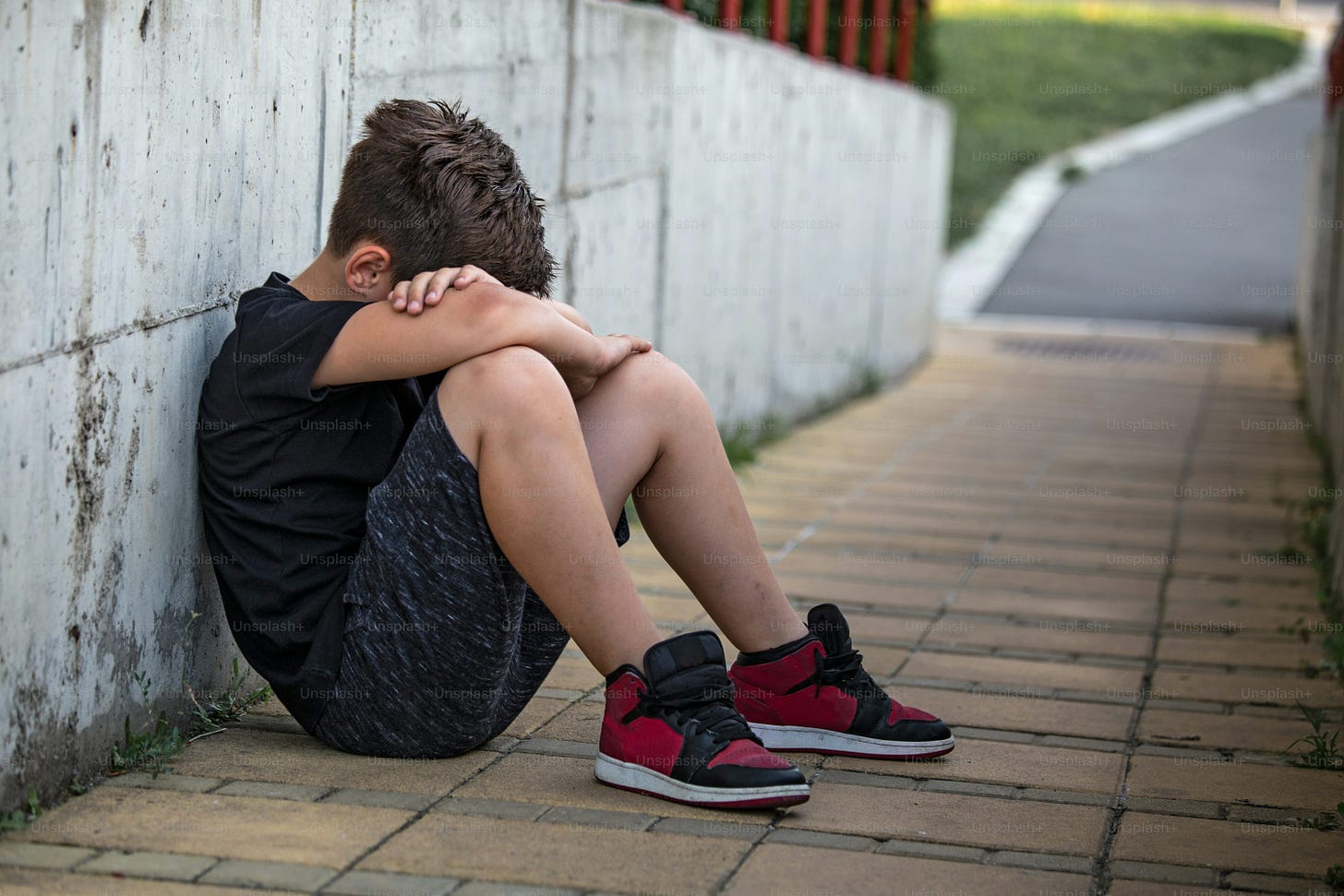 Little boy sad sitting alone at school hides his face. Isolation and bullying concept. Kid sad and unhappy, child was crying, upset, feel sick Little boy sad sitting alone at school hides his face. Isolation and bullying concept. Kid sad and unhappy, child was crying, upset, feel sick