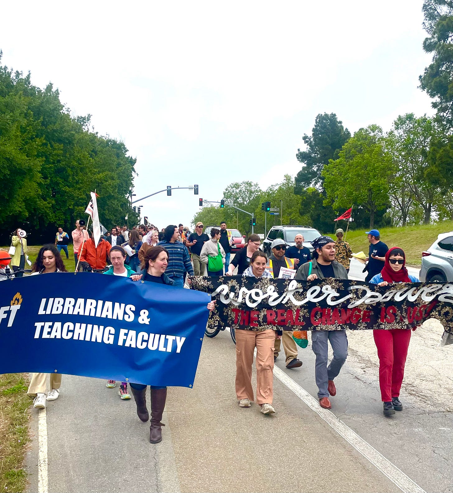 union members marching down a street with a banner union members marching down a street with a banner