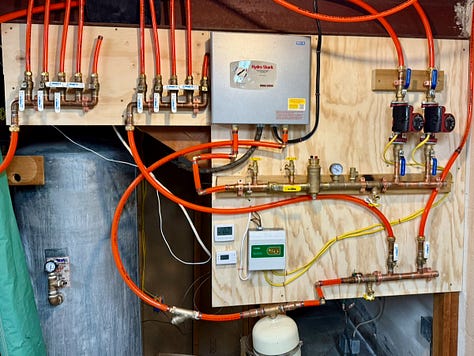 Close-up images show copper and brass plumbing fittings, including a soldered joint and a pressure gauge mounted on a pipe. The final image shows the fully assembled hydronic heating system mounted on plywood, with PEX tubing, manifolds, pumps, wiring, and control components neatly arranged.