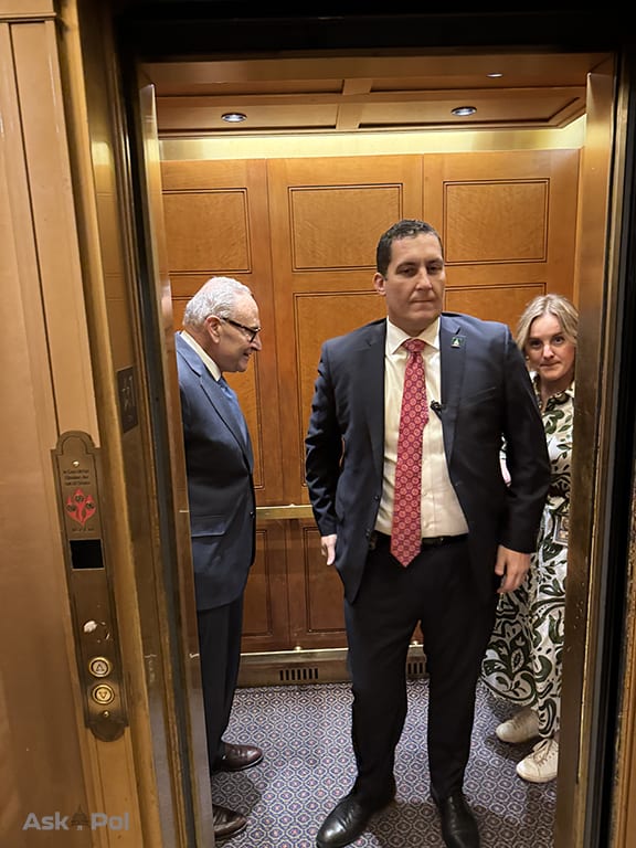 A security officer smiles as someone photographs his politician boss as they board a private elevator. Photo: Matt Laslo for www.askapol.com