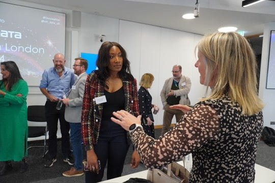 Vouchsafe’s  Nkechi Anyanwu chatting with other attendees in a presentation room.