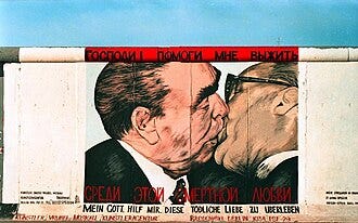 Mural del artista ruso Dmitri Vrúbel en la East Side Gallery de Berlín, pintado en 1990, que reproduce el célebre beso entre los dos mandatarios. La leyenda en ruso y alemán dice: “Dios mío, ayúdame a sobrevivir a este amor mortal”. Este graffiti se convirtió en una atracción turística y en un símbolo visual de la Guerra Fría.